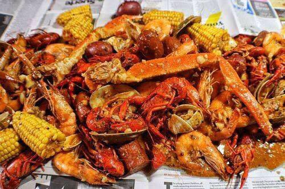 Seafood boil with crab, shrimp, crawfish, clams, potatoes, and corn on newspaper