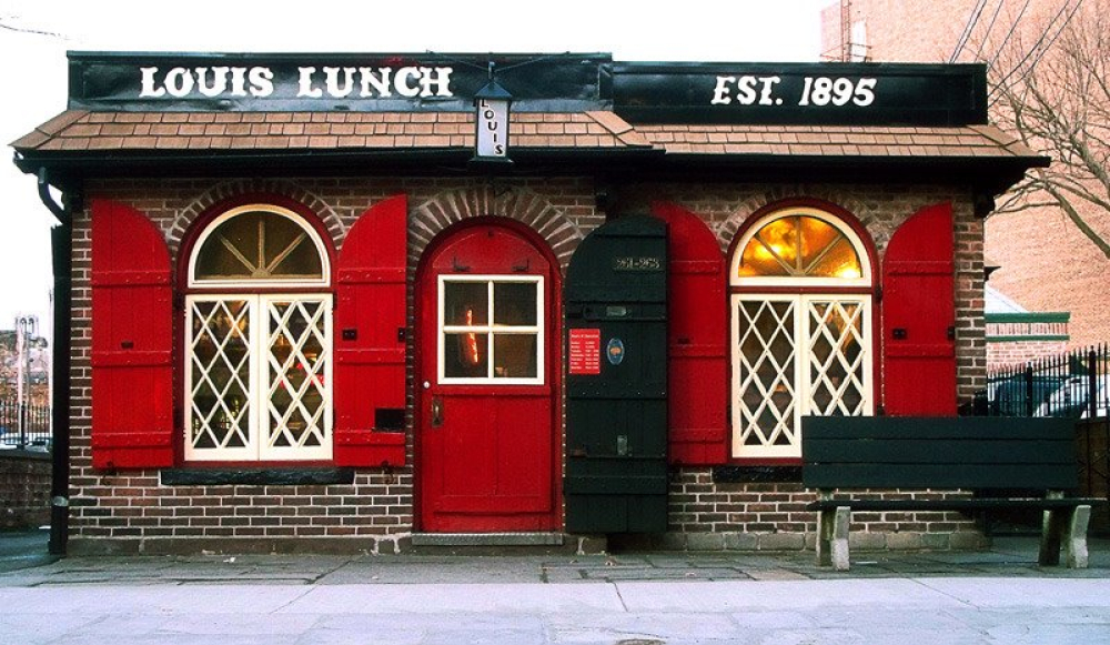 Historic Louis Lunch restaurant with red shutters and door, established 1895