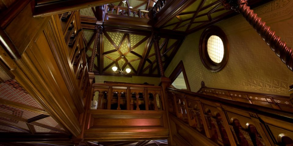 Intricate wooden staircase with patterned ceiling and round window