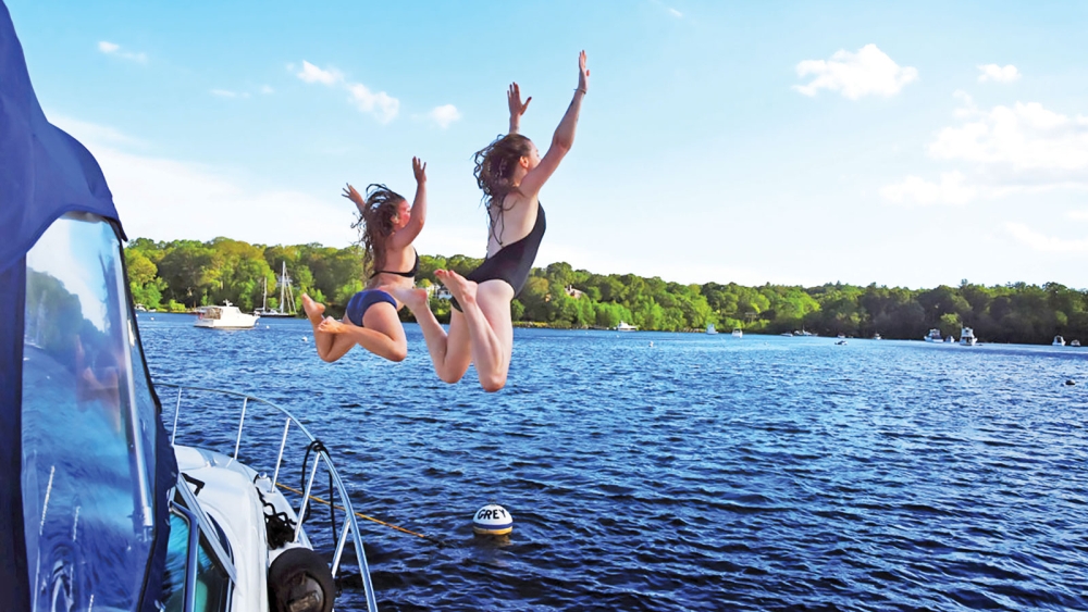 Two girls jumping off a boat into a lake in CT