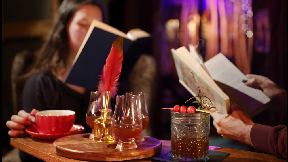 Los invitados leen libros en una mesa con té y cócteles.
