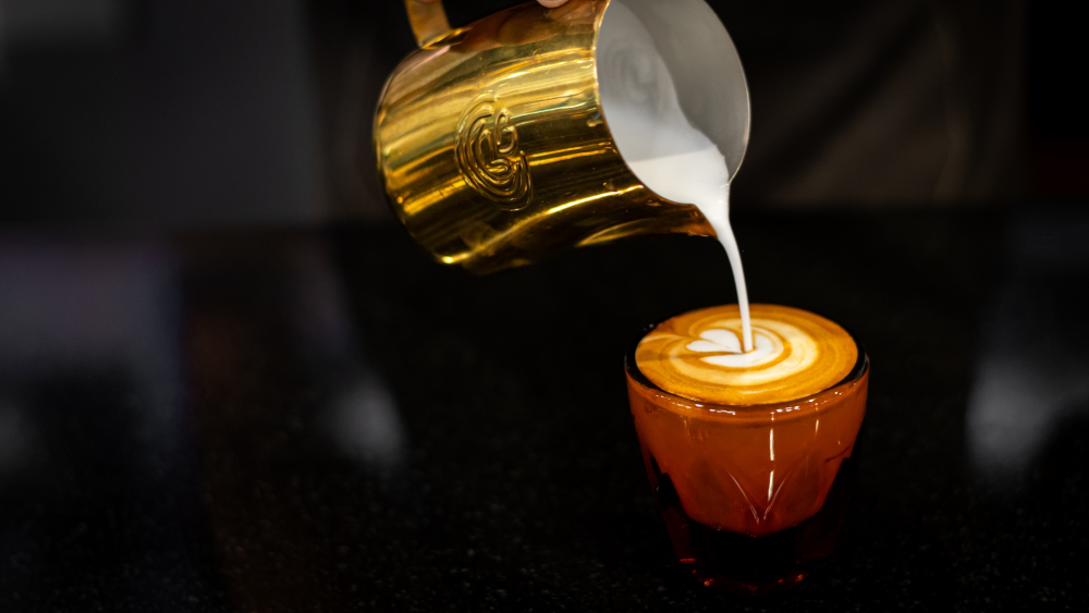 Un barista vierte leche en un café con leche en Victus Coffee en Hartford.