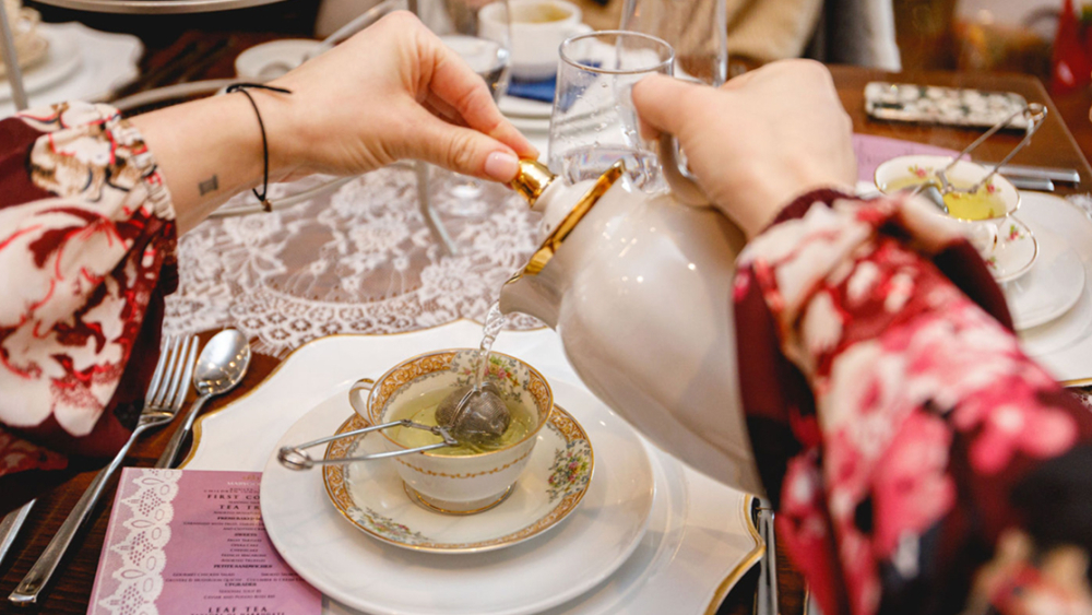 Manos sirviendo té en una taza en Marygold's on Main, Newtown.
