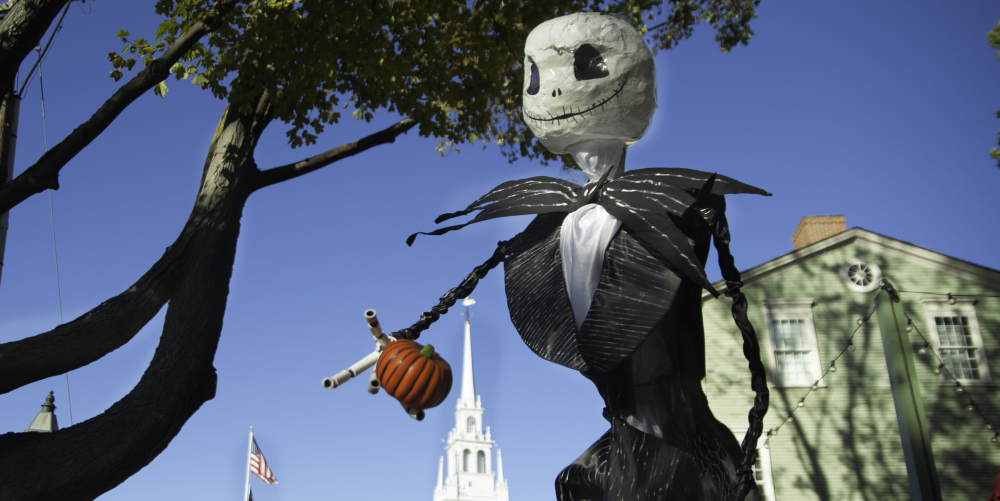 Una imagen de un espantapájaros sosteniendo una calabaza. 