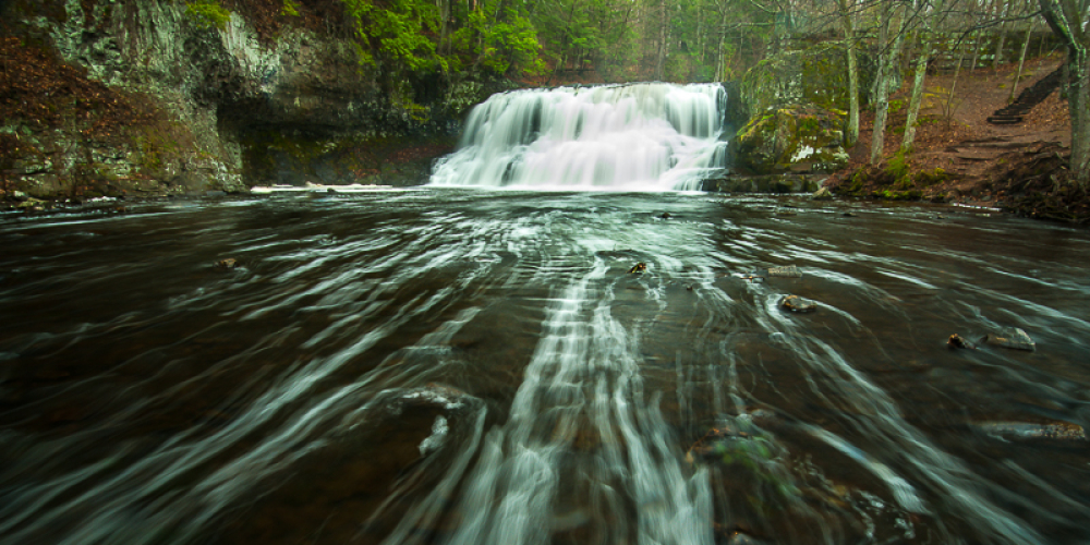 Wadsworth Falls cascading over rocks into flowing river surrounded by trees