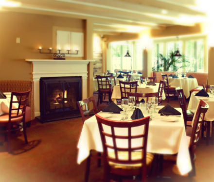 Cozy dining room with fireplace, set tables, and large windows