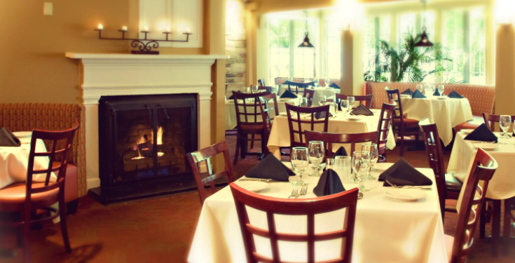 Cozy dining room with fireplace, set tables, and large windows