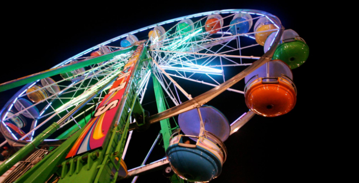 Colorful Ferris wheel lit up at night against black sky