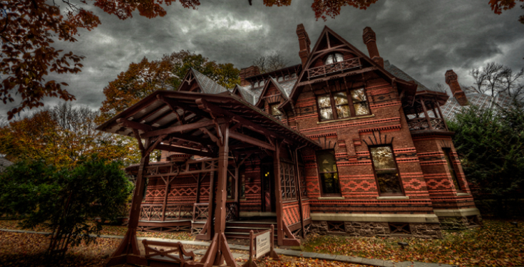 Victorian brick house under cloudy sky in autumn with wooden porch