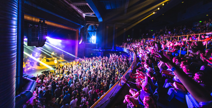 Crowd enjoying live concert with stage lights and band performing