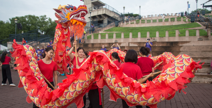 Group performing traditional red and gold Chinese dragon dance outdoors