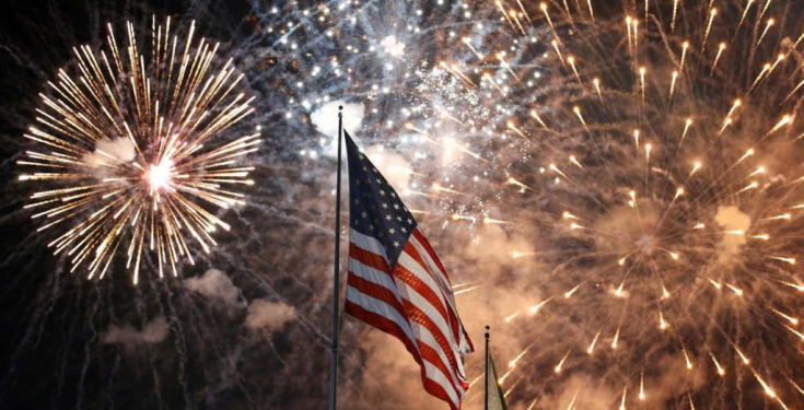 American flag with colorful fireworks exploding in night sky