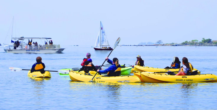 A school group experiences a rotation of three classes: kayaking, on-the-water water quality lab testing, and sailing