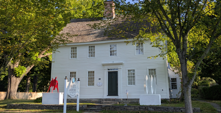 Pratt House in summer with leafy trees and modern art on display