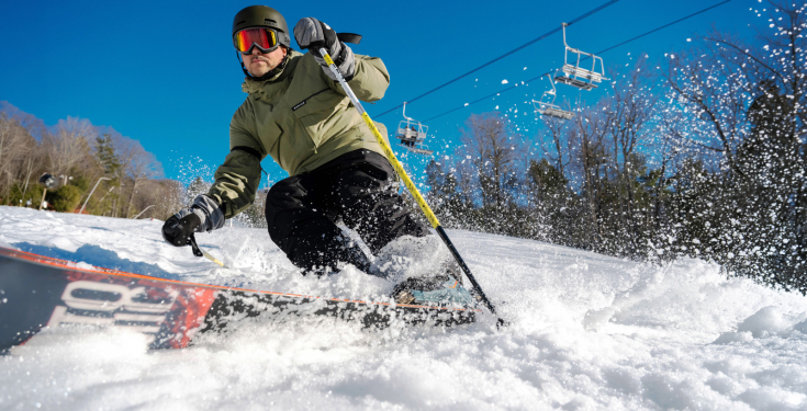 Skier carving on trail and creating snow spray